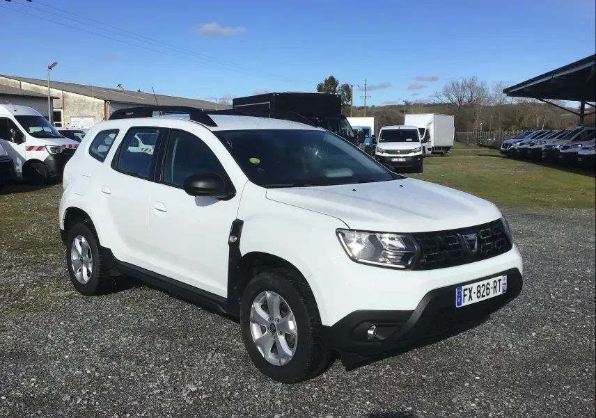 Dacia Duster blanc en 3/4 avant droit, SUV compact avec calandre noire et jantes alliage 16 pouces.