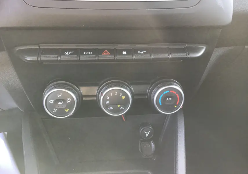 Vue rapprochée du tableau de bord du Dacia Duster 2021, montrant les commandes de climatisation et les boutons de fonction.