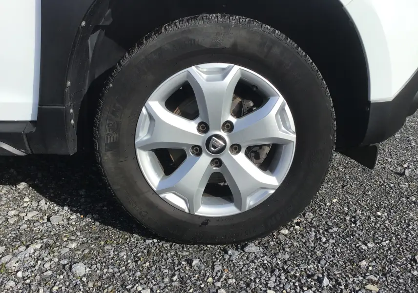 Gros plan sur la roue avant droite du Dacia Duster blanc 2021 avec jante alliage 16 pouces et logo central Dacia.