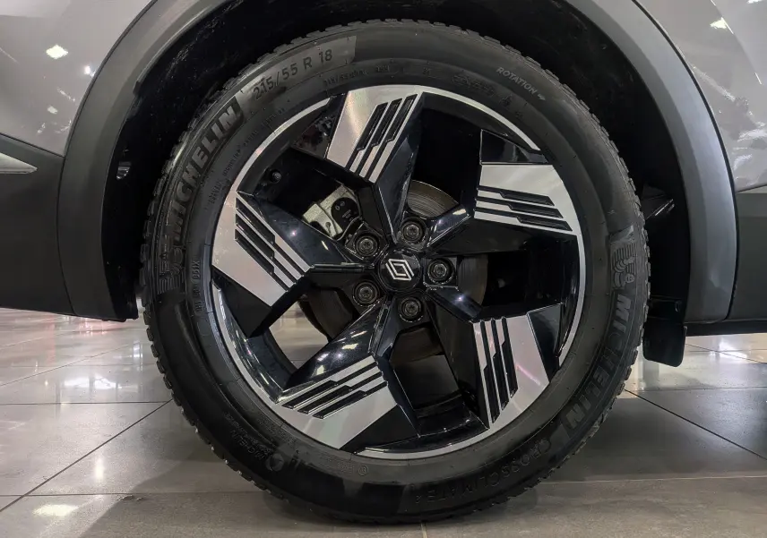 Gros plan sur la jante bi-ton noire et argentée avec logo Renault, montée sur un pneu Michelin, sur une carrosserie gris Cassiopé.