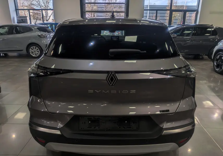 Vue arrière du Renault SYMBIOZ gris Cassiopé en showroom, avec logo et nom du modèle bien visibles sur le hayon.
