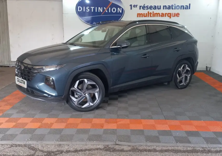 Vue 3/4 avant droit d'un Hyundai Tucson gris foncé stationné en intérieur avec jantes alliage distinctives.