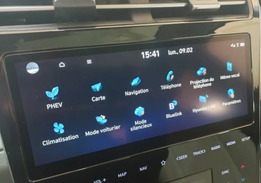 Écran tactile central du Hyundai Tucson gris foncé 2023 affichant les menus PHEV, navigation et climatisation.