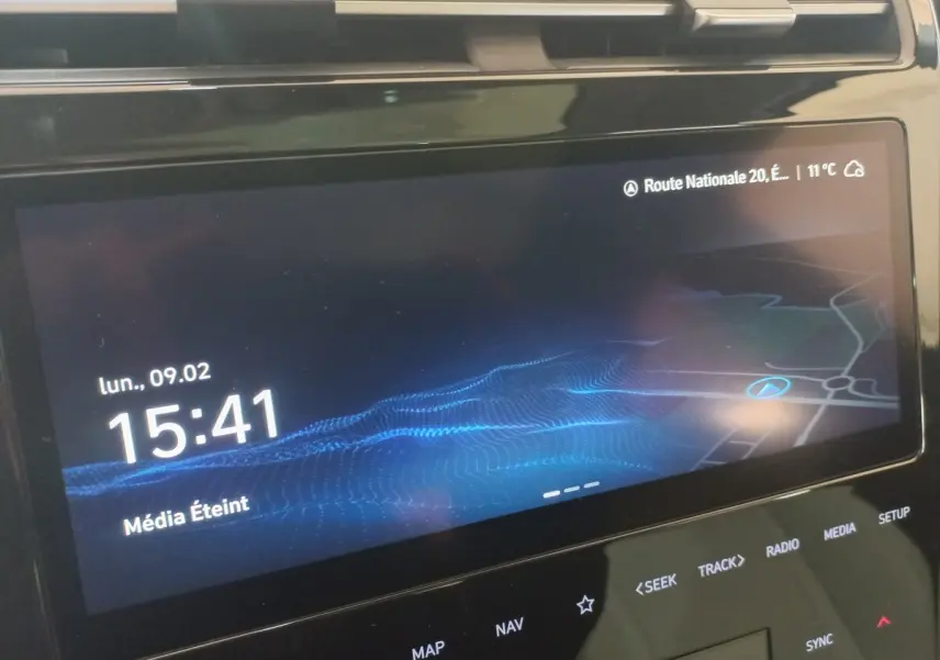 Écran tactile central du Hyundai Tucson gris foncé 2023 affichant l'heure et la navigation.