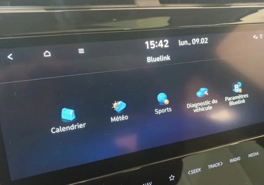 Écran tactile central du Hyundai Tucson 2023 affichant les applications Bluelink sur fond noir, vue rapprochée.
