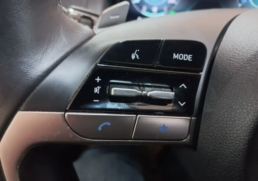 Gros plan sur les commandes gauche du volant du Hyundai Tucson gris foncé, boutons mode, volume et appel.