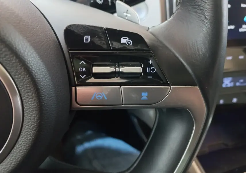 Gros plan sur les commandes du volant à droite du Hyundai Tucson gris foncé, avec boutons de régulateur et assistance conduite.