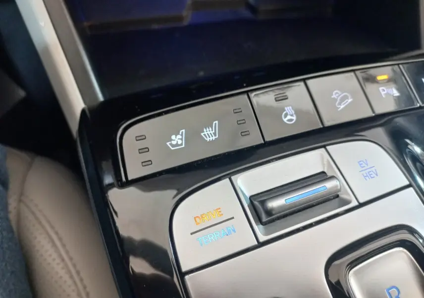 Vue rapprochée du panneau de commandes central gris et noir du Hyundai Tucson 2023 avec boutons de réglage de conduite et sièges chauffants/ventilés.