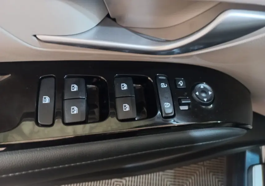 Gros plan sur les commandes de lève-vitres et rétroviseurs côté conducteur du Hyundai Tucson gris foncé 2023.