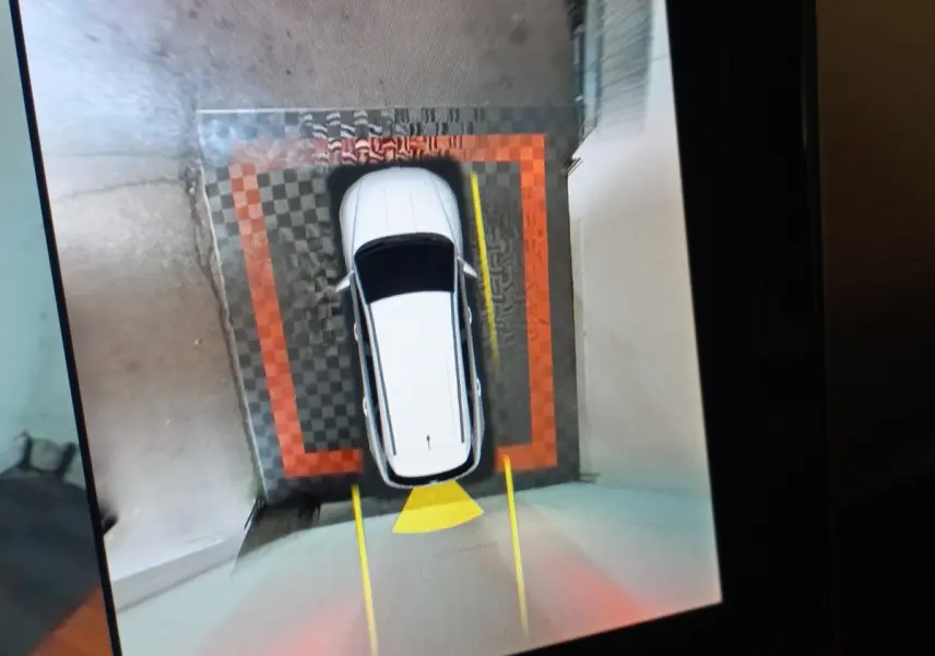 Vue aérienne du Hyundai Tucson gris foncé en stationnement assisté, avec marquages au sol visibles autour du véhicule.