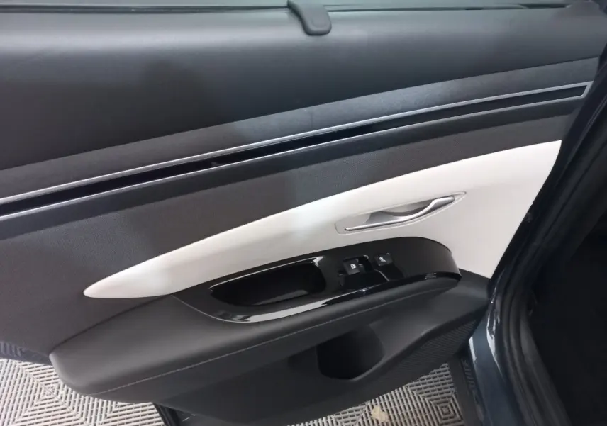 Vue rapprochée de la porte avant droite du Hyundai Tucson gris foncé, avec garniture intérieure bicolore noire et blanche.