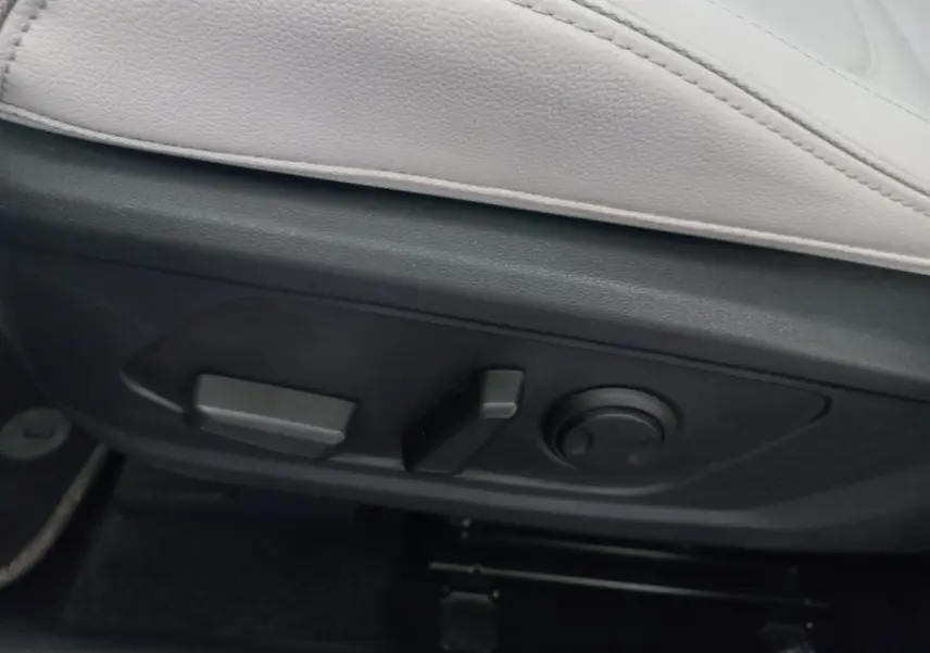 Vue rapprochée des commandes de réglage électrique du siège avant en cuir clair du Hyundai Tucson gris foncé 2023.