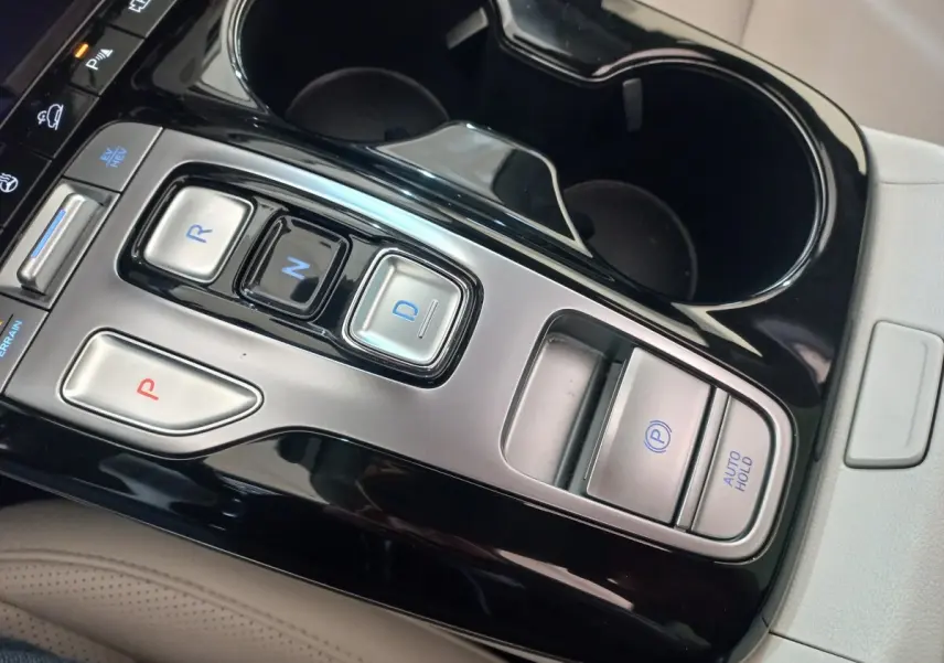 Gros plan sur la console centrale noire et argentée du Hyundai Tucson 2023, boutons de boîte auto et frein électrique visibles.