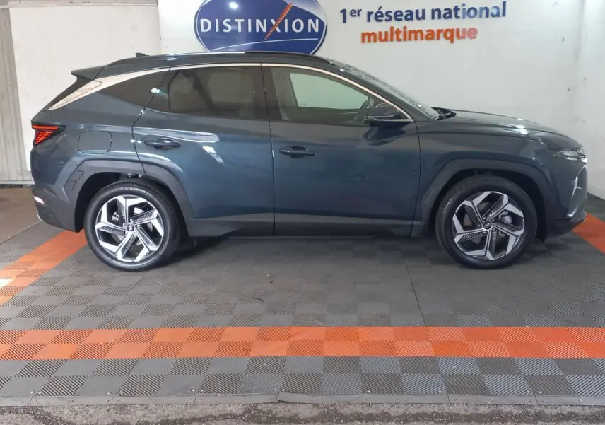 Vue latérale droite du Hyundai Tucson 1.6 PHEV gris foncé, avec jantes alliage et vitres teintées, en intérieur showroom.