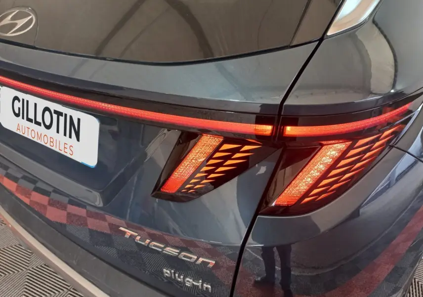 Gros plan arrière droit du Hyundai Tucson gris foncé avec feux LED allumés et logo Tucson visible.