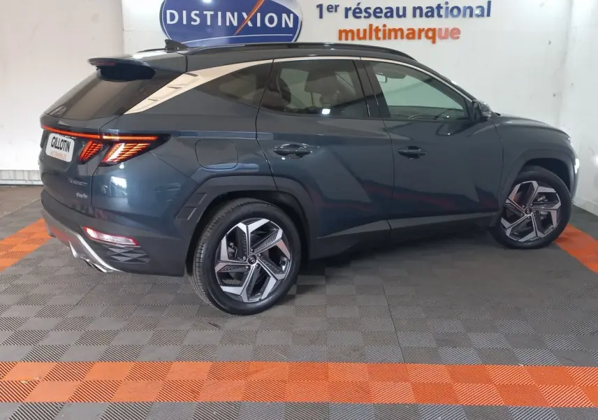 Vue profil droit d’un Hyundai Tucson gris foncé 2023 avec feux arrière LED allumés dans un showroom.