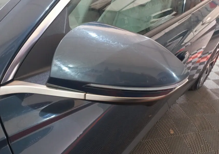 Rétroviseur côté gauche gris foncé du Hyundai Tucson 2023, avec clignotant intégré et carrosserie visible en arrière-plan.