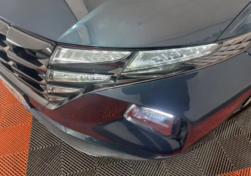 Gros plan sur l'avant droit gris foncé du Hyundai Tucson 2023, mettant en valeur les phares LED et la calandre chromée.