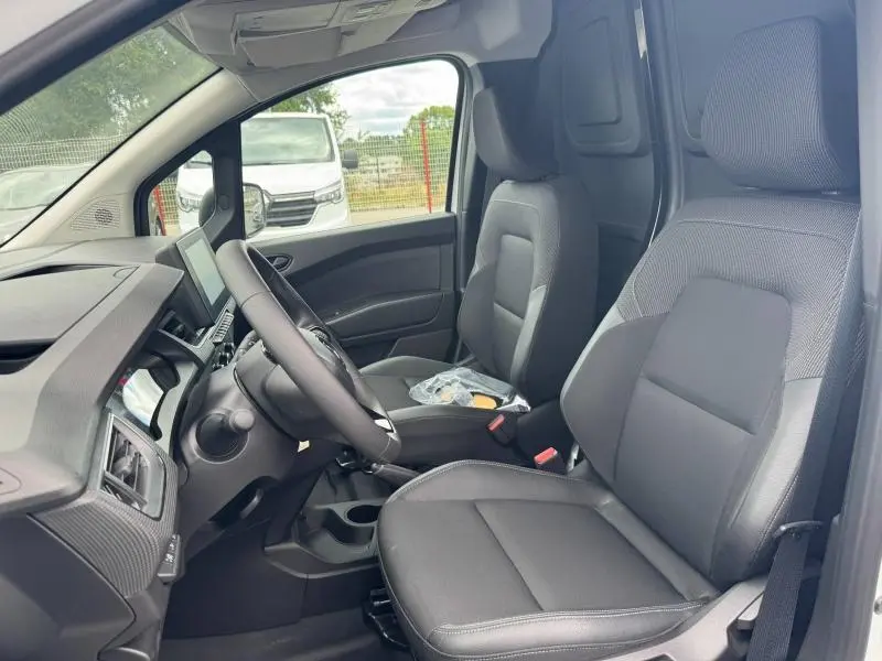 Vue intérieure côté conducteur du Renault Kangoo Van blanc 2024, sièges en tissu noir avec accoudoir central.