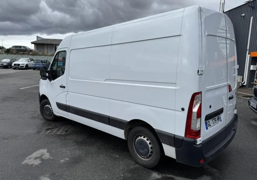 Renault Master blanc en vue 3/4 arrière droit, fourgon utilitaire avec portes arrière tôlées ouvertes à 180° et baguettes latérales noires.