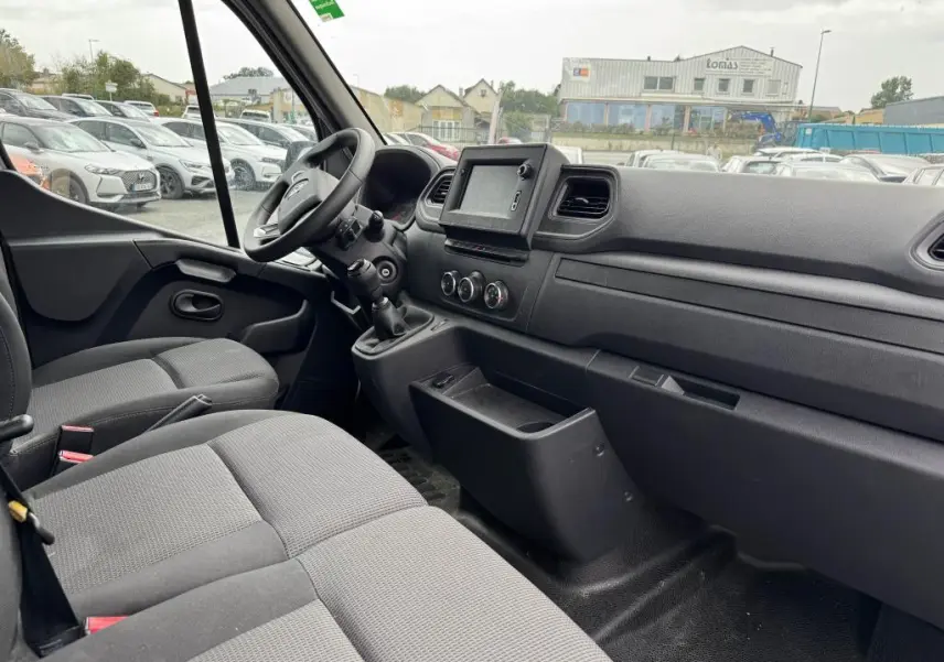 Intérieur cabine Renault Master 2022 vu côté passager, sièges tissu gris et tableau de bord avec écran tactile.
