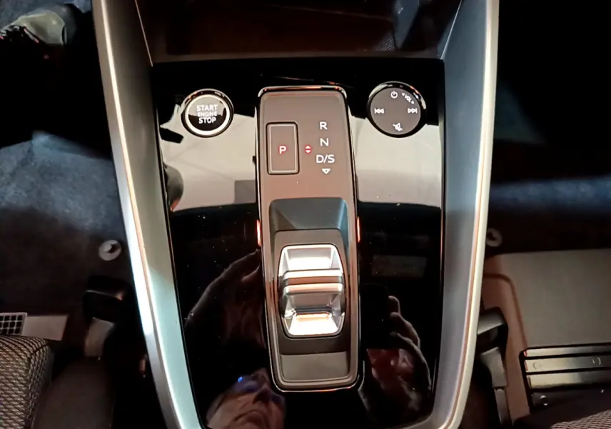 Gros plan sur la console centrale noire brillante de l'Audi A3 35 TFSI 2023 avec levier de vitesses et bouton start/stop.