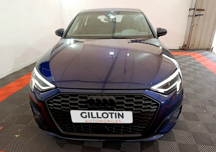 Vue avant d'une Audi A3 35 TFSI bleu nuit avec calandre noire et phares LED allumés en intérieur.
