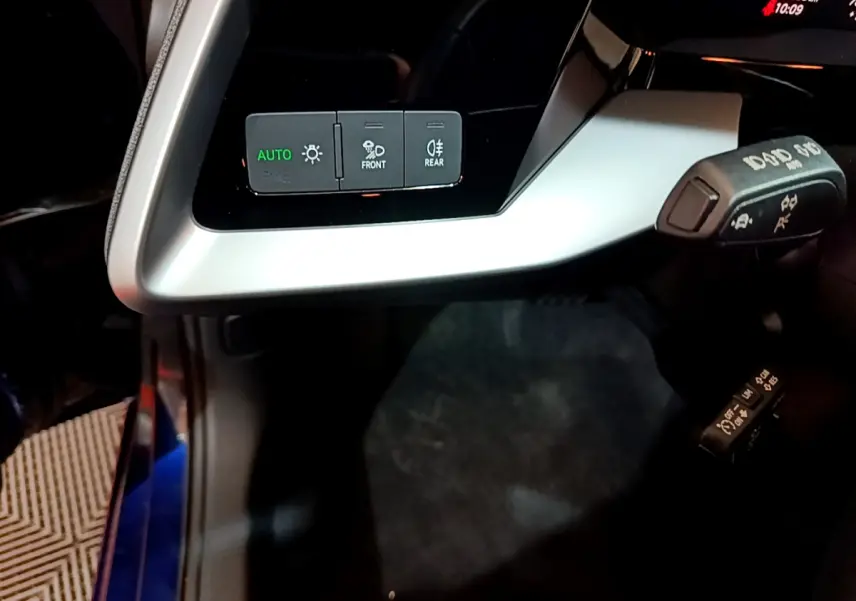 Gros plan sur les commandes d'éclairage et les leviers de la colonne de direction dans l'habitacle d'une Audi A3 bleu 2023.