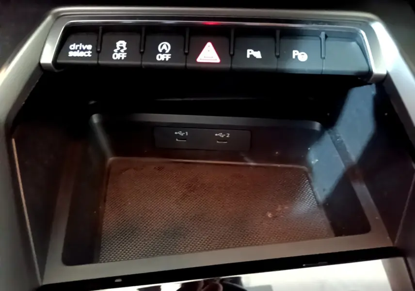 Gros plan sur la console centrale noire de l'Audi A3 35 TFSI 2023 avec boutons de contrôle et ports USB visibles.