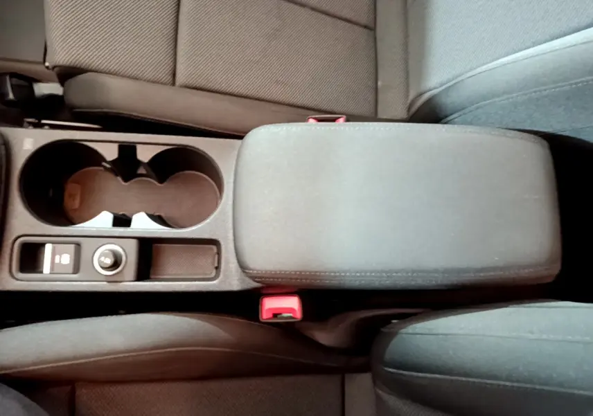 Vue plongeante sur la console centrale noire de l'Audi A3 35 TFSI 2023 avec accoudoir et porte-gobelets.