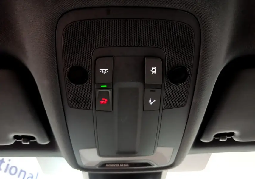 Vue en plongée du panneau de commandes au plafond intérieur de l'Audi A3 bleu 2023 avec bouton SOS rouge et éclairage.