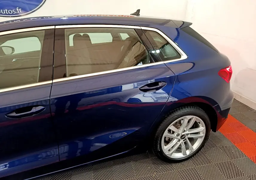 Vue côté droit arrière d'une Audi A3 35 TFSI bleu métallisé avec jante alliage et feux arrière LED.