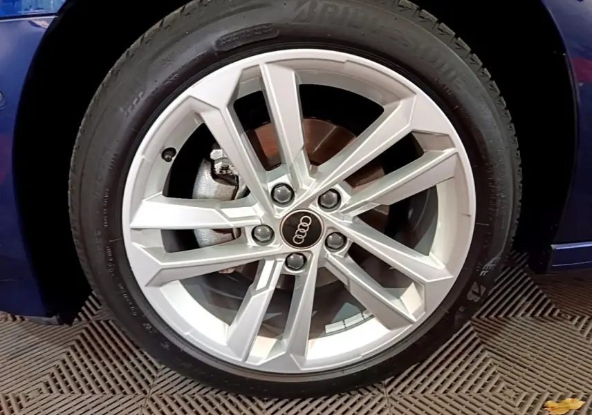 Gros plan sur la roue avant gauche d'une Audi A3 bleu 2023 avec jante alliage argentée à design moderne.