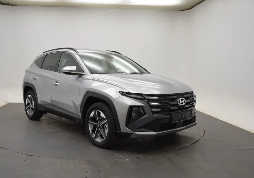 Hyundai Tucson 2025 hybride en Shimmering Silver, vue 3/4 avant droit avec jantes 18 pouces et vitres teintées.
