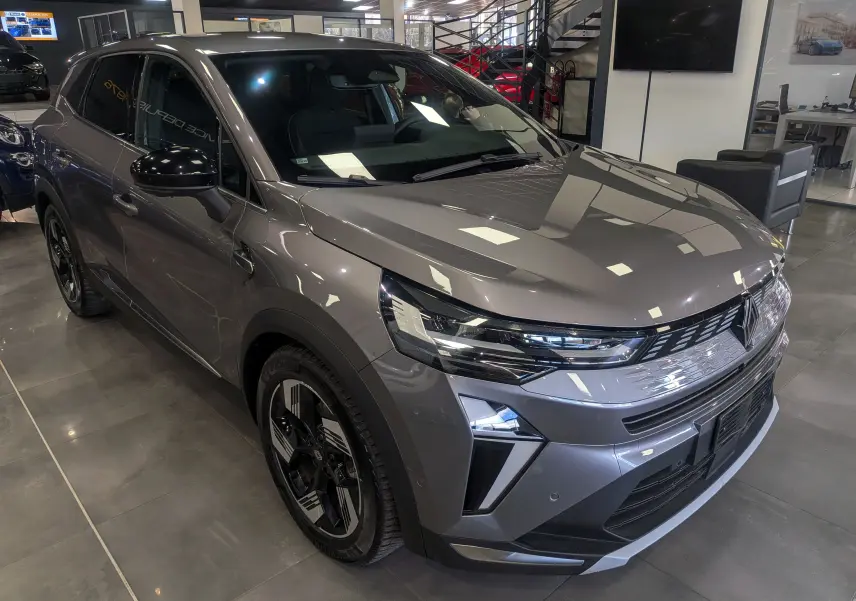 Renault Symbioz E-Tech Full Hybrid gris Cassiopé, vue 3/4 avant droit, avec calandre lumineuse et jantes bicolores.