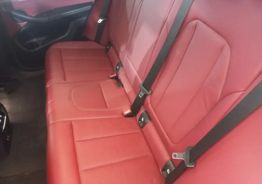 Vue rapprochée de la banquette arrière rouge avec ceintures noires du BMW X3 xDrive30e 2022 blanc.