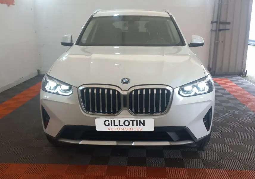Vue frontale d’un BMW X3 blanc avec phares LED allumés et calandre double haricot caractéristique.