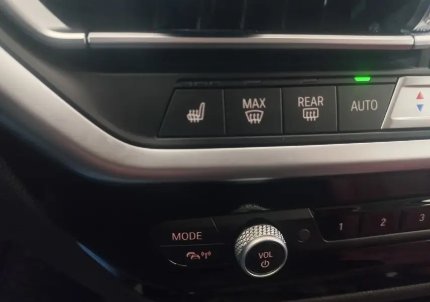 Gros plan sur la console centrale du BMW X3 blanc, montrant les commandes de chauffage et le bouton volume.