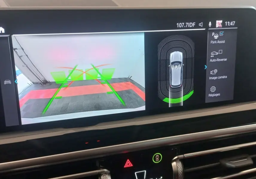 Écran tactile intérieur montrant l'aide au stationnement et la caméra de recul du BMW X3 blanc, vue de face.