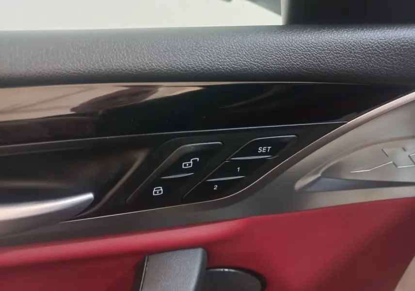 Détail de la porte intérieure côté conducteur du BMW X3 blanc 2022 avec garniture rouge et commandes de verrouillage.