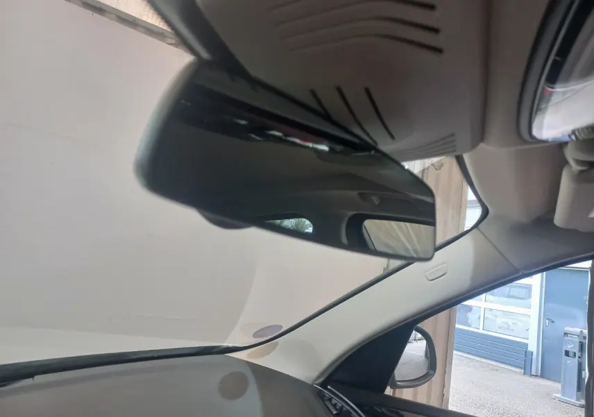 Vue intérieure centrée sur le rétroviseur intérieur d’un BMW X3 blanc, avec partie du tableau de bord et vitre côté droit visible.