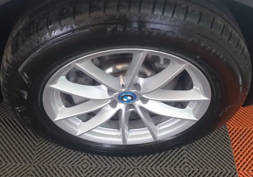 Gros plan sur la jante argentée avec logo BMW d'un BMW X3 blanc, pneu Bridgestone visible.
