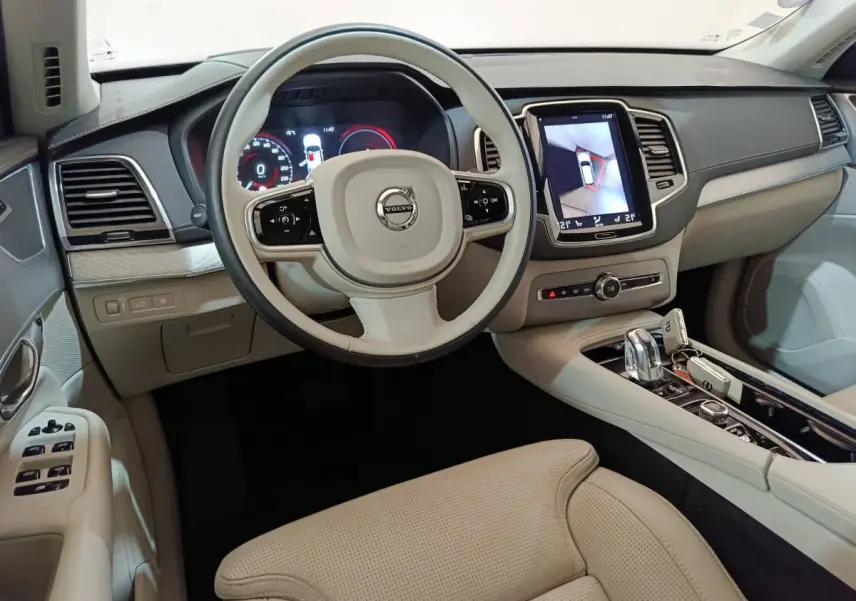 Intérieur beige clair du Volvo XC90 T8, vue depuis le siège conducteur sur volant et écran tactile central.