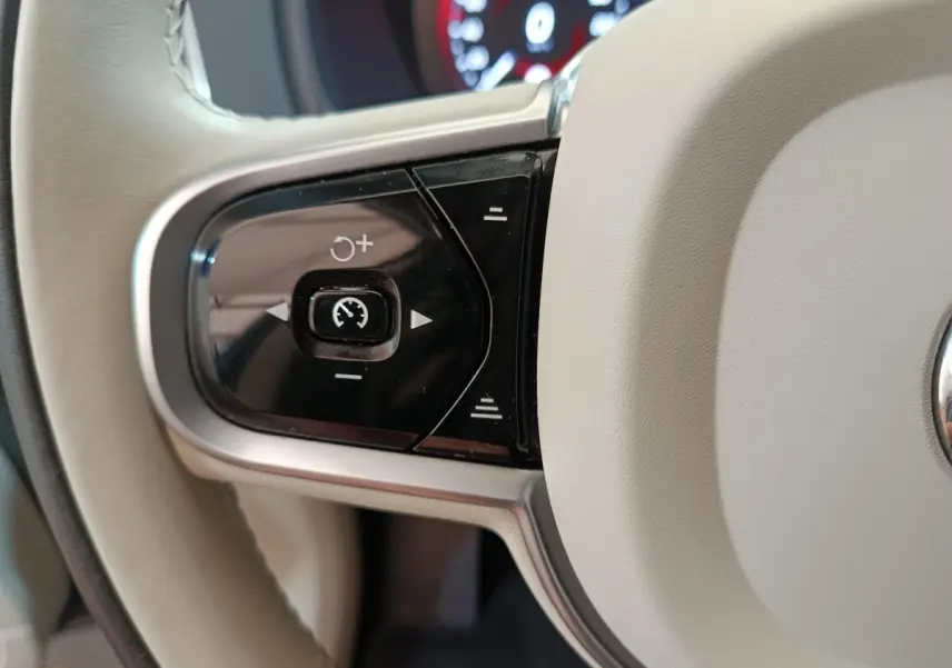 Gros plan sur les commandes de régulateur de vitesse au volant cuir beige du Volvo XC90 T8 hybride rechargeable.