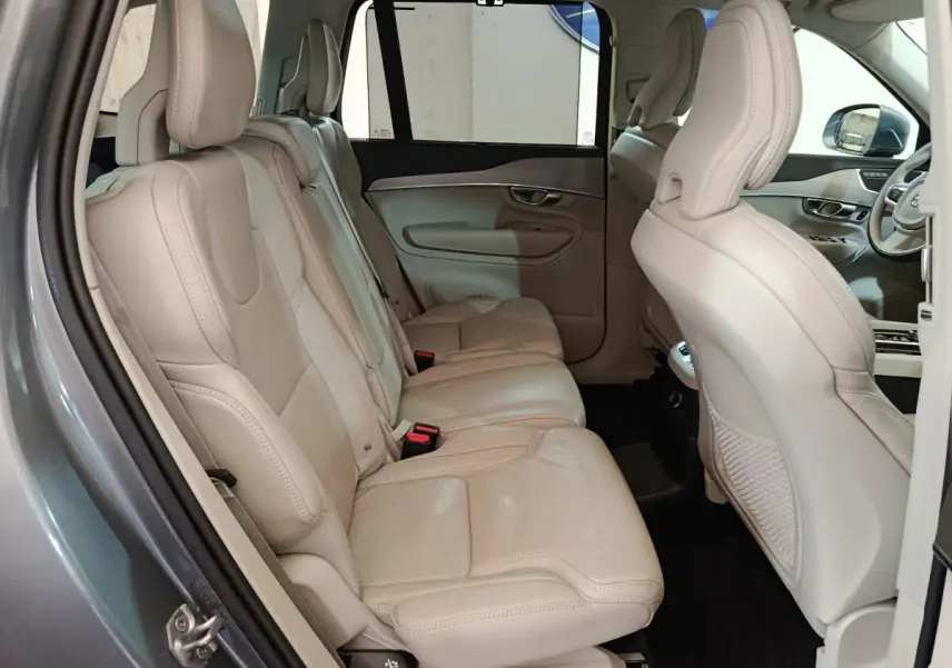 Vue côté gauche sur l'intérieur beige cuir du Volvo XC90 T8 hybride, mettant en valeur les sièges arrière spacieux.