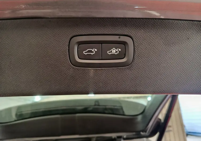 Gros plan sur les boutons d'ouverture et verrouillage électrique du coffre du Volvo XC90 gris clair, vue intérieure du hayon.