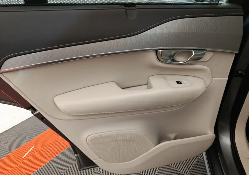 Gros plan sur la porte arrière droite beige et noire du Volvo XC90 T8, avec poignée chrome et commande de vitre.
