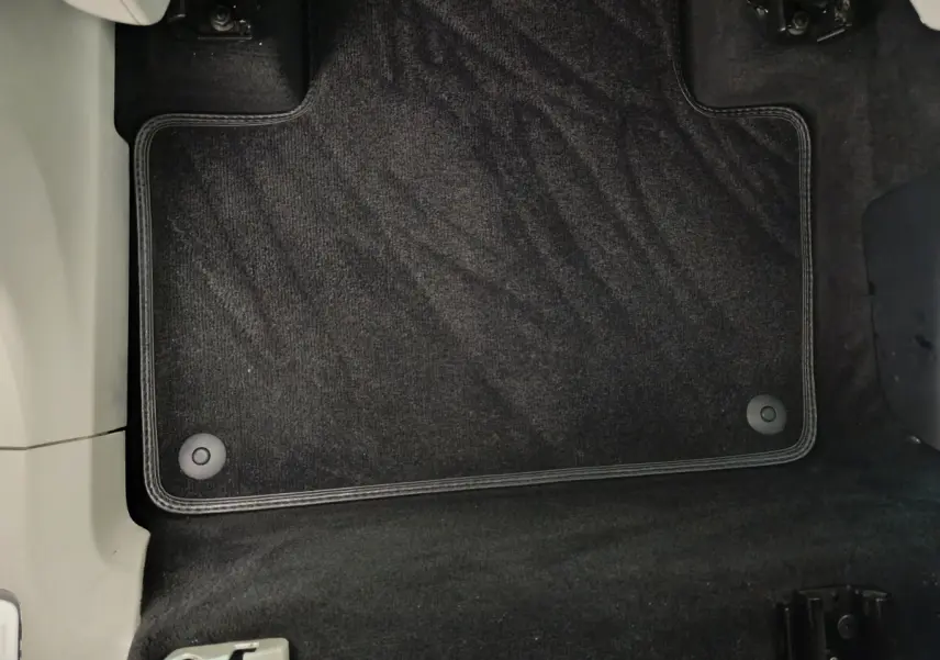 Tapis de sol noir côté conducteur dans l'habitacle d'un Volvo XC90 T8 gris clair, vue rapprochée.