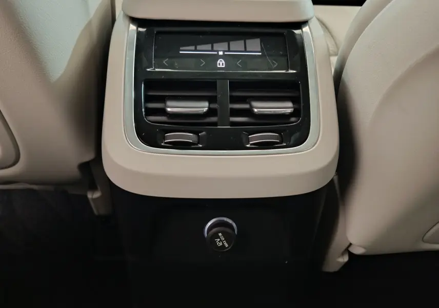 Vue rapprochée de la console arrière beige du Volvo XC90 T8 avec commandes de climatisation et prise 12V.