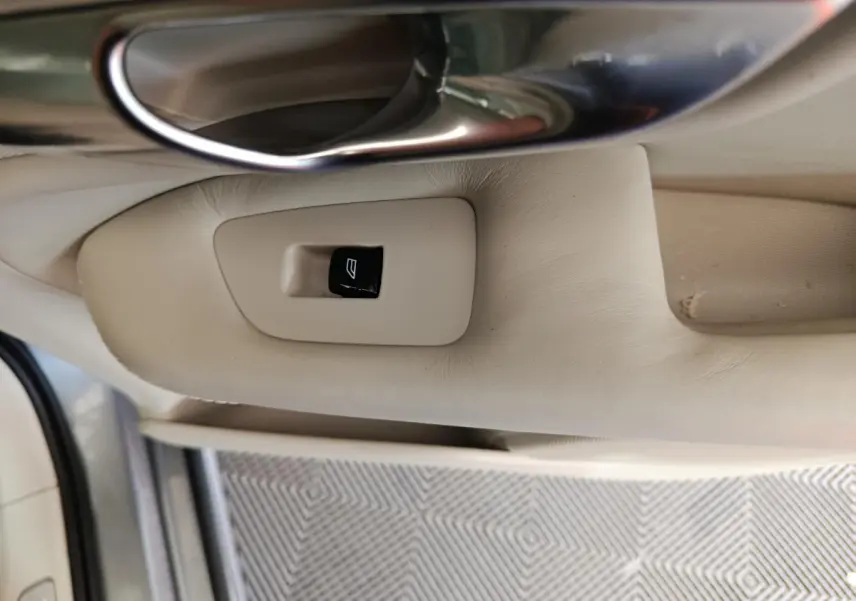 Gros plan sur la commande de lève-vitre beige côté gauche intérieur d'un Volvo XC90 gris clair de 2019.